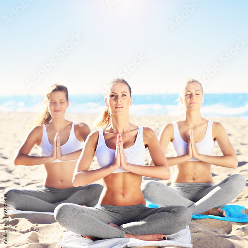 Group of women practising yoga on the beach
