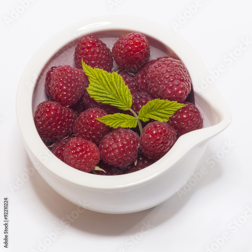 Ripe raspberry with leaf in a bowl