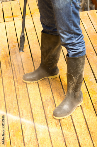 Man wearing rubber boots using high water pressure cleaner on