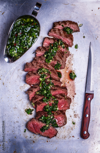 Obraz na plátne Sliced beef barbecue steak with chimichurri sauce