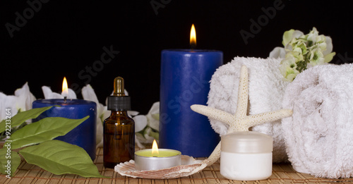 Bottle with spa essence spa candles flowers and cream