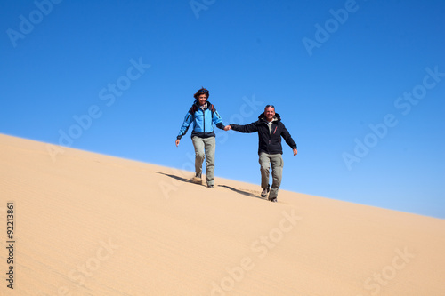 Coppia felice che corre sulla sabbia del deserto