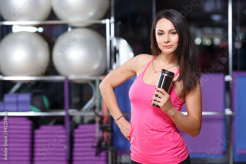 Young athletic woman posing with black cup in her hand