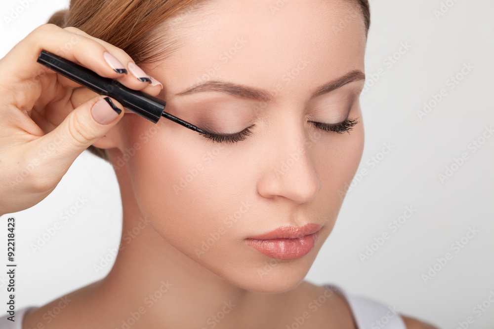 Skilled young beautician is doing make-up for girl