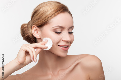 Cheerful healthy woman is cleaning her face