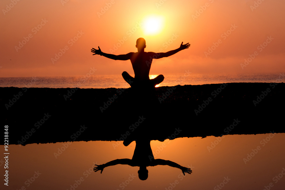 Young man silhouette on the beach,welcoming the sunrise in yoga posture