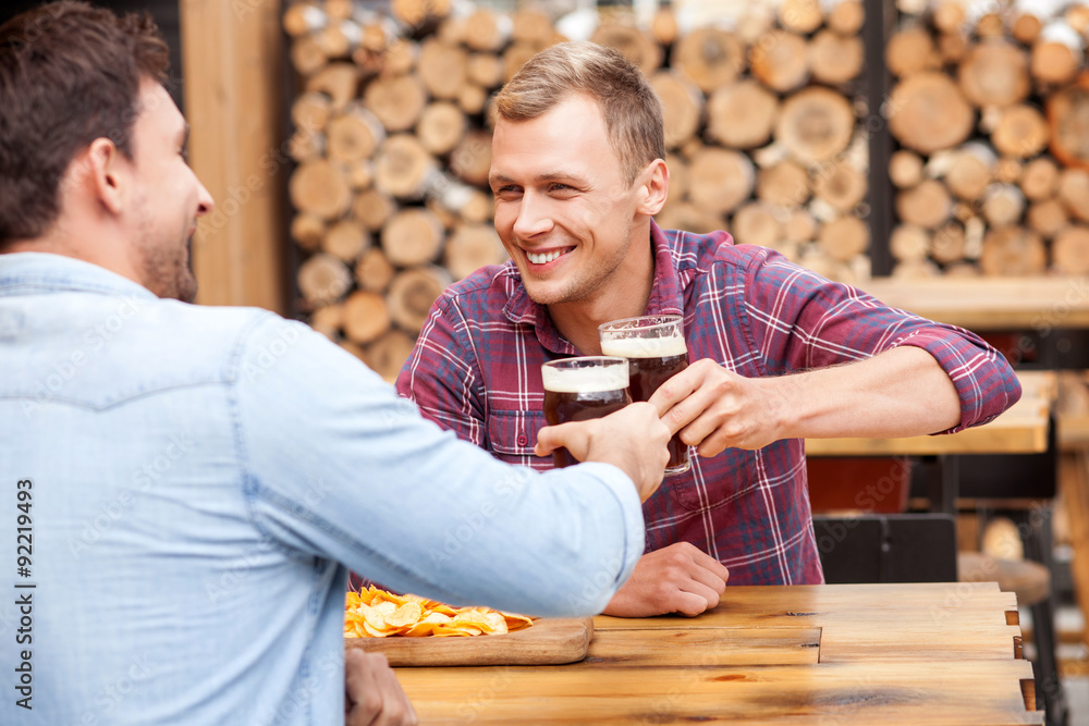Handsome young guys are swigging lager in bar Handsome young guys are swigging lager in bar