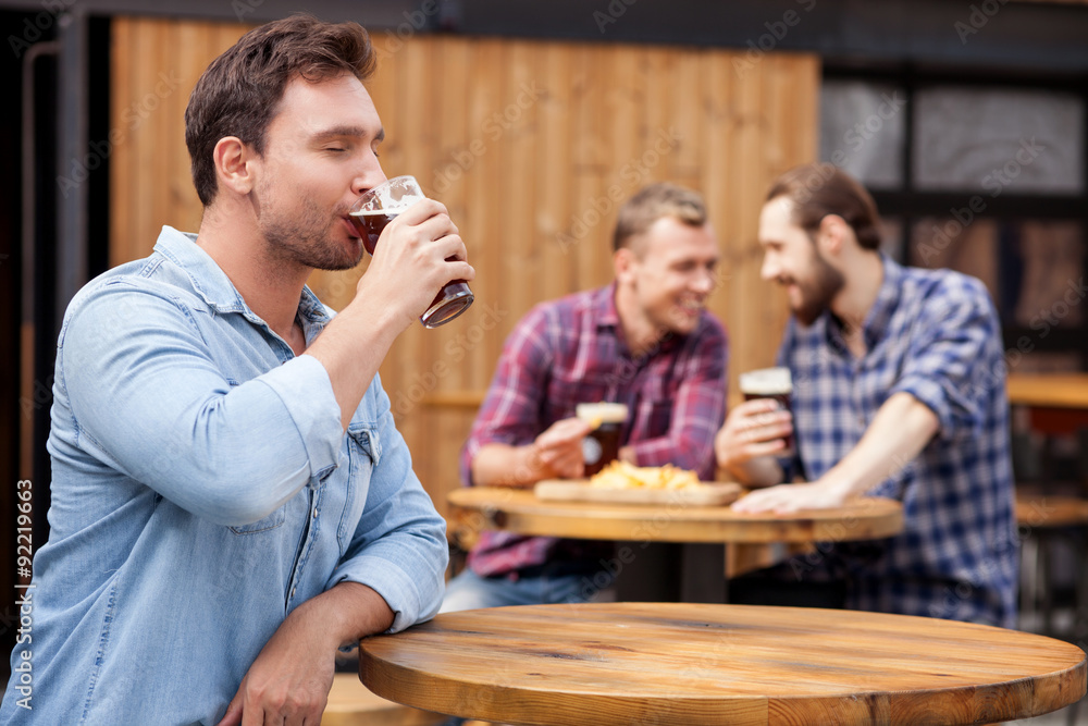 Cheerful young guy is swigging lager in bar Cheerful young guy is swigging lager in bar