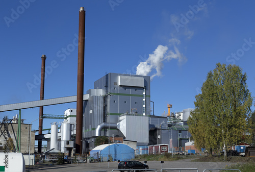 A factory with chimneys and smoke on a blue sky