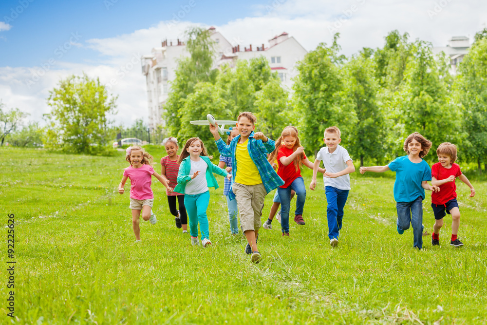 Obraz premium Boy holds big white airplane toy and kids behind