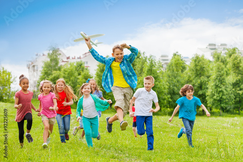 Jumping boy holding big airplane toy and children
