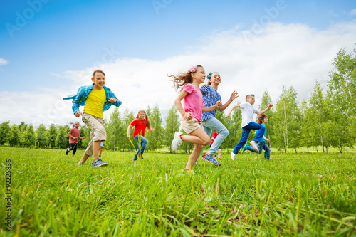 Fototapeta Naklejka Na Ścianę i Meble -  Children are running through green field together