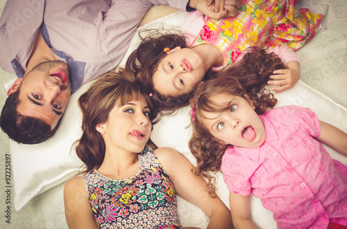Young adorable hispanic sisters and parents lying down with