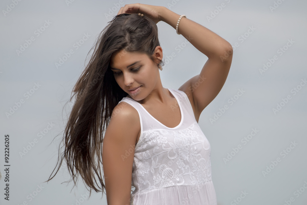 Close view of a beautiful woman on a white dress over a blue sky.