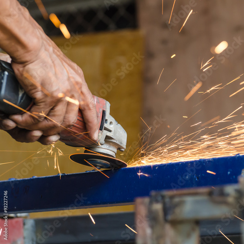 Electric wheel grinding on steel structure in factory