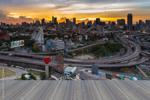 Opeing wooden floor of Bangkok skyline with highway overpass intersection with city sunset background, Thailand photo