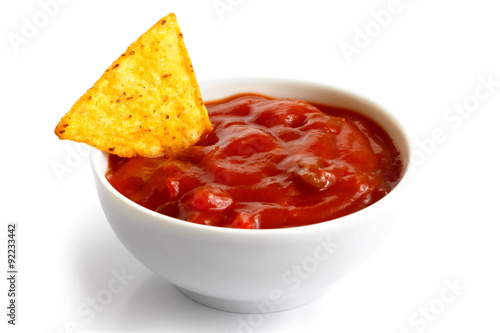 Round white bowl of tomato salsa dip isolated in perspective. To