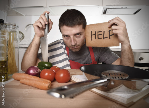 Obraz na plátně young man at home kitchen in cook apron desperate in cooking stress