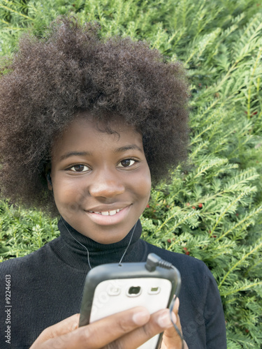 Afro girl listening to music in a park photo