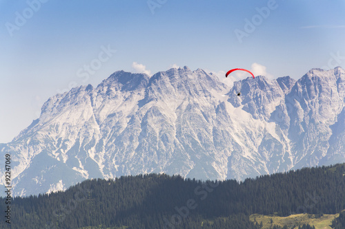 Paraglider flyes over mountains in Alps, Austria