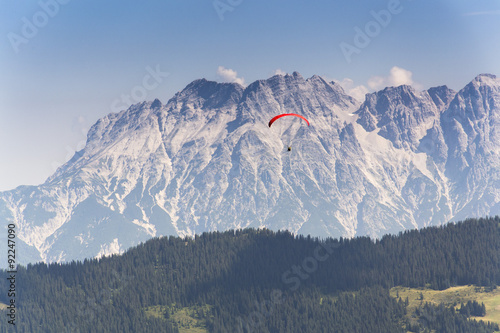 Paraglider flyes over mountains in Alps, Austria