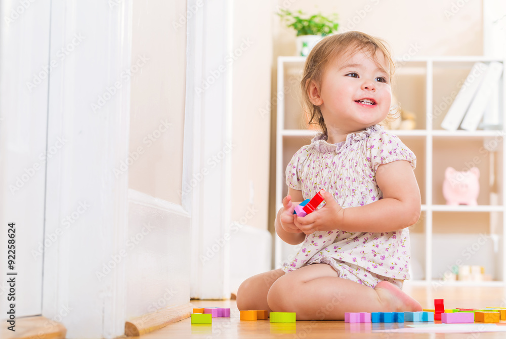 Toddler smiling and playing with wooden toy blocks Toddler smiling and playing with wooden toy blocks