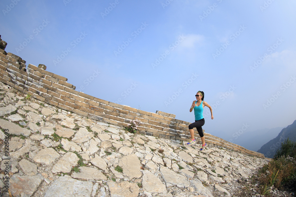 woman runner athlete running on trail at chinese great wall . woman fitness jogging workout wellness concept.