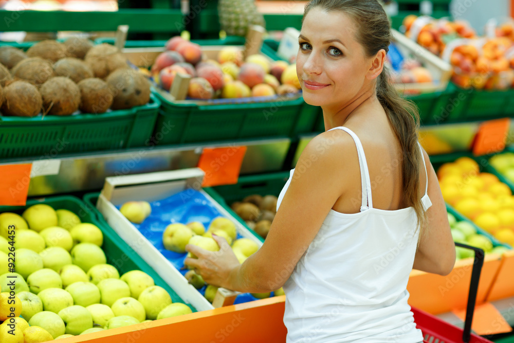 Young woman shopping in a supermarket in the department of fruit