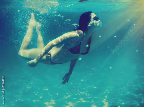 Young girl swimming under water. Vintege style picture