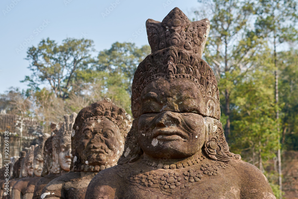 Statues of ancient khmer warrior heads carry giant snake decorating bridge to Bayon at Angkor Wat complex, Siem Reap, Cambodia.