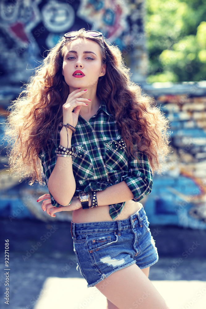 Naklejka premium beautiful teenage girl posing near graffiti wall