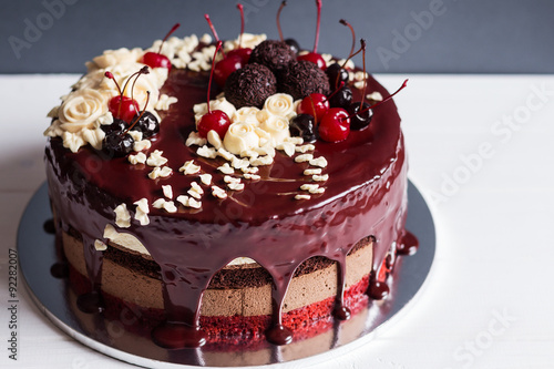 Layer cake decorated with chocolate glaze, cream flowers and che