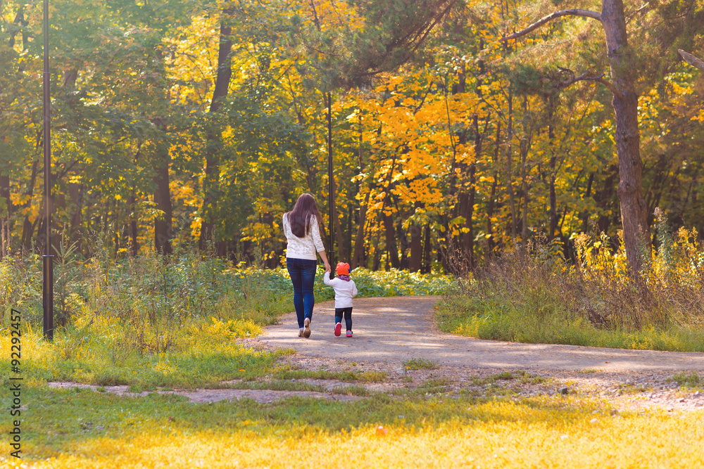 Fototapeta premium Young mother walking with her baby in an autumn park