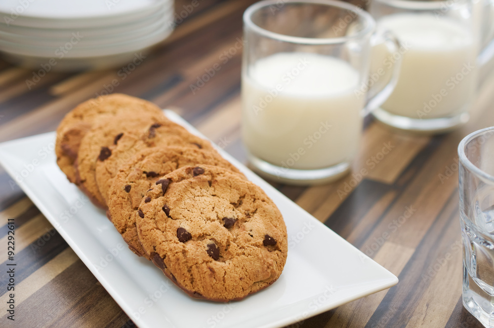 Chocolate chip cookies and milk on dark wood table Chocolate chip cookies and milk on dark wood table