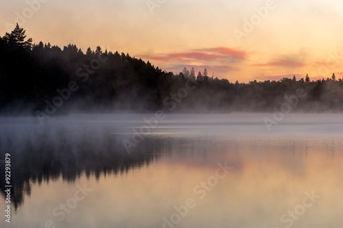 View over lake befoer the sun rises, with vivid colors in the sky and mist on the water