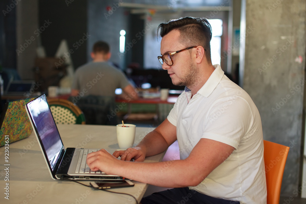 Stylish man using laptop in startup office Stylish man using laptop in startup office