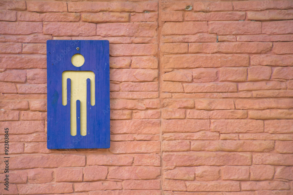 The blue men toilet symbol with brick wall in background. The blue men toilet symbol with brick wall in background.