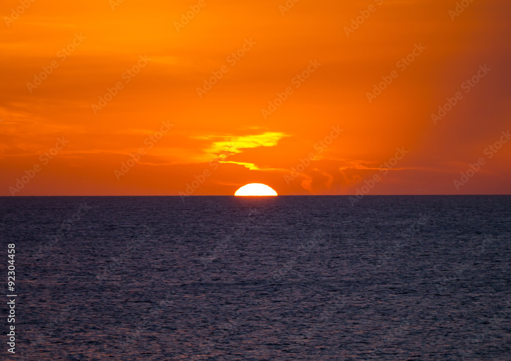 El sol poniéndose en el Mediterráneo con el cielo naranja, en Menorca, Islas Baleares, España
