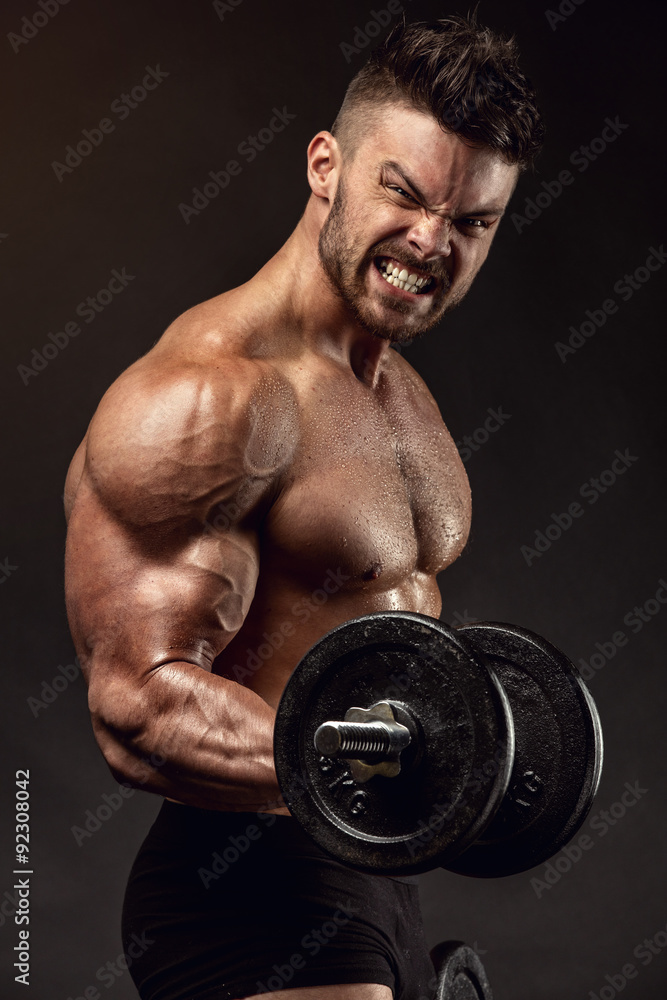 Muscular bodybuilder guy doing exercises with dumbbells Muscular bodybuilder guy doing exercises with dumbbells