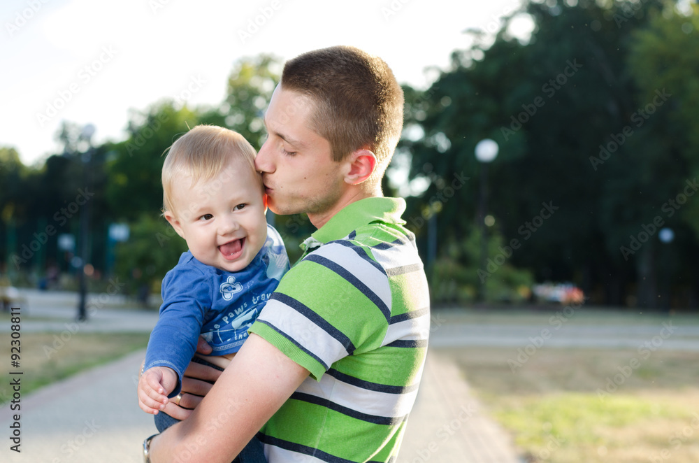 Fototapeta premium young father is holding and kissing his little son