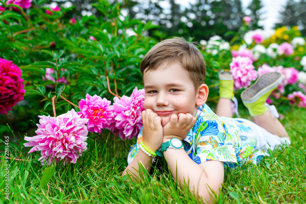Thoughtful and dreamy boy is lying on the green grass in summer Thoughtful and dreamy boy is lying on the green grass in summer