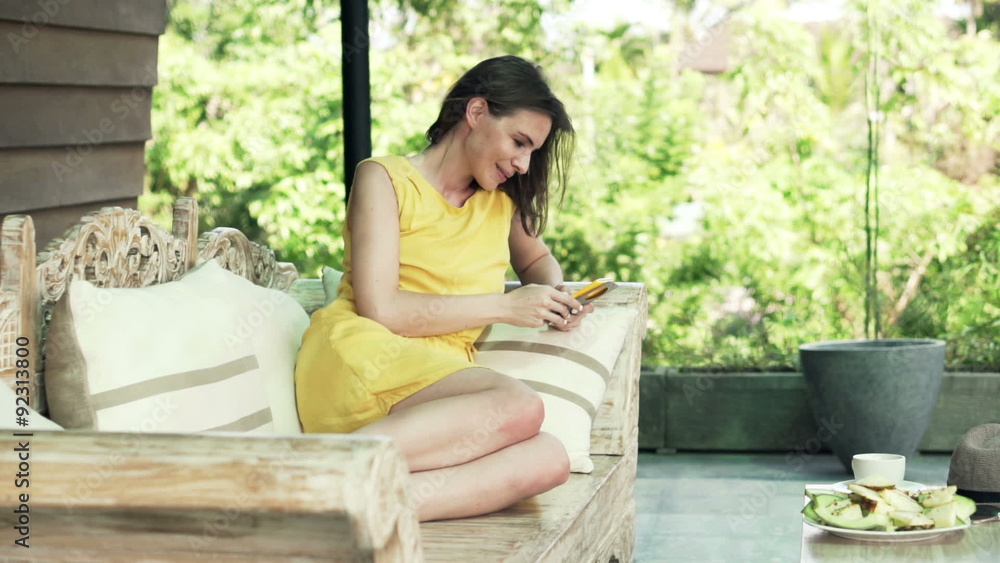 Young, happy woman using smartphone sitting on sofa on terrace
Young, happy woman using smartphone sitting on sofa on terrace
