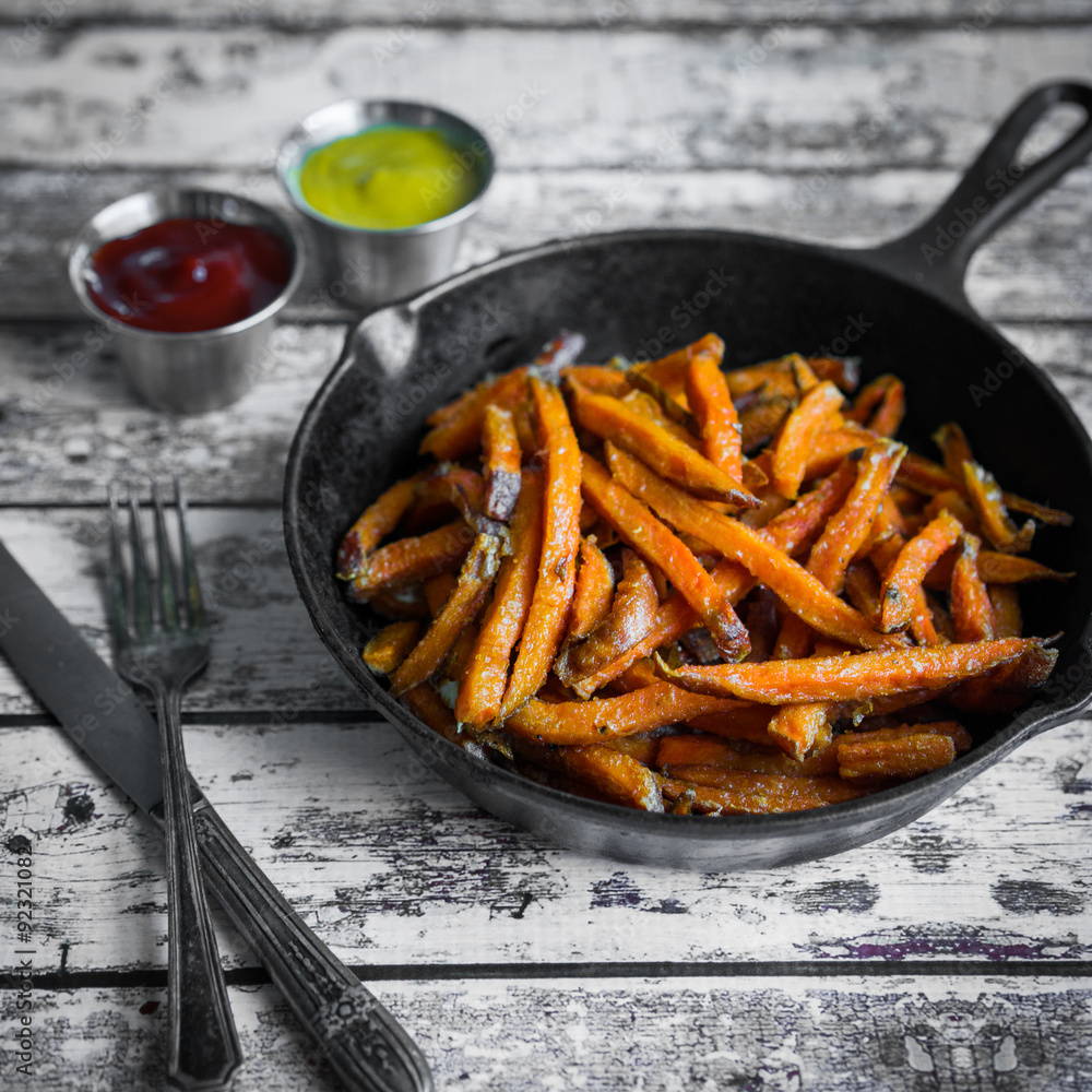 Sweet potato fries in cast iron skillet on wooden background Sweet potato fries in cast iron skillet on wooden background