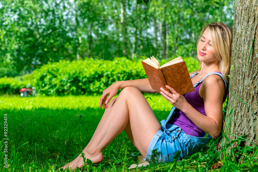attractive young woman reading a novel in the park sitting near attractive young woman reading a novel in the park sitting near