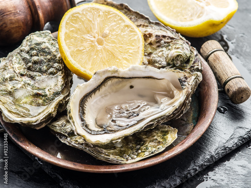 Obraz na plátně Raw oysters on the graphite board.