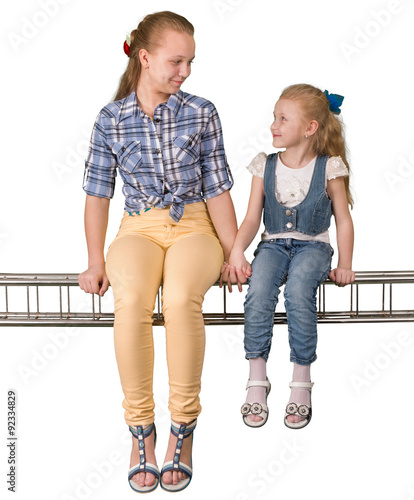 Two girls sitting on the beam isolated on white background