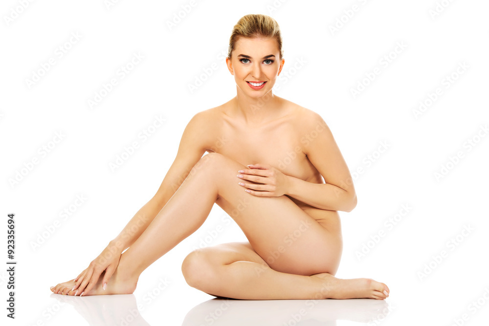 Fototapeta premium Young woman sitting on the floor and touching her legs