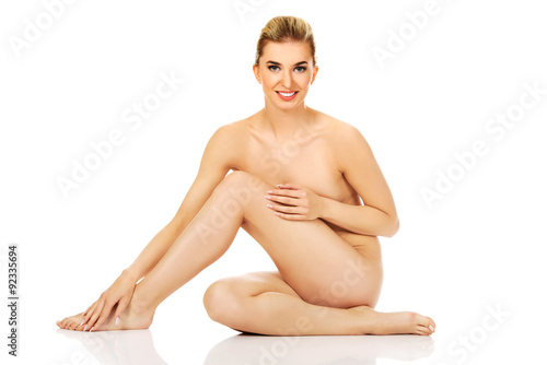 Young woman sitting on the floor and touching her legs
