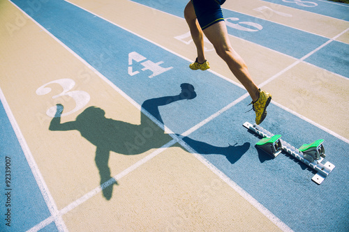 Fotografi Athlete in gold shoes sprinting from the starting blocks over the starting line