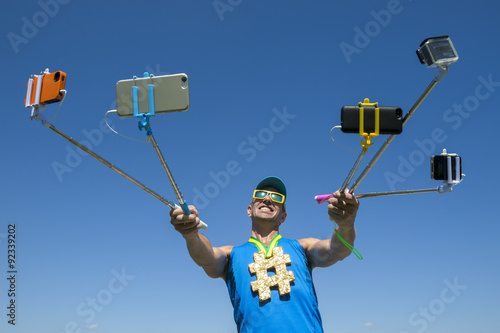 Hashtag gold medal athlete smiling for his many gadgets on selfie sticks as he poses for a picture photo